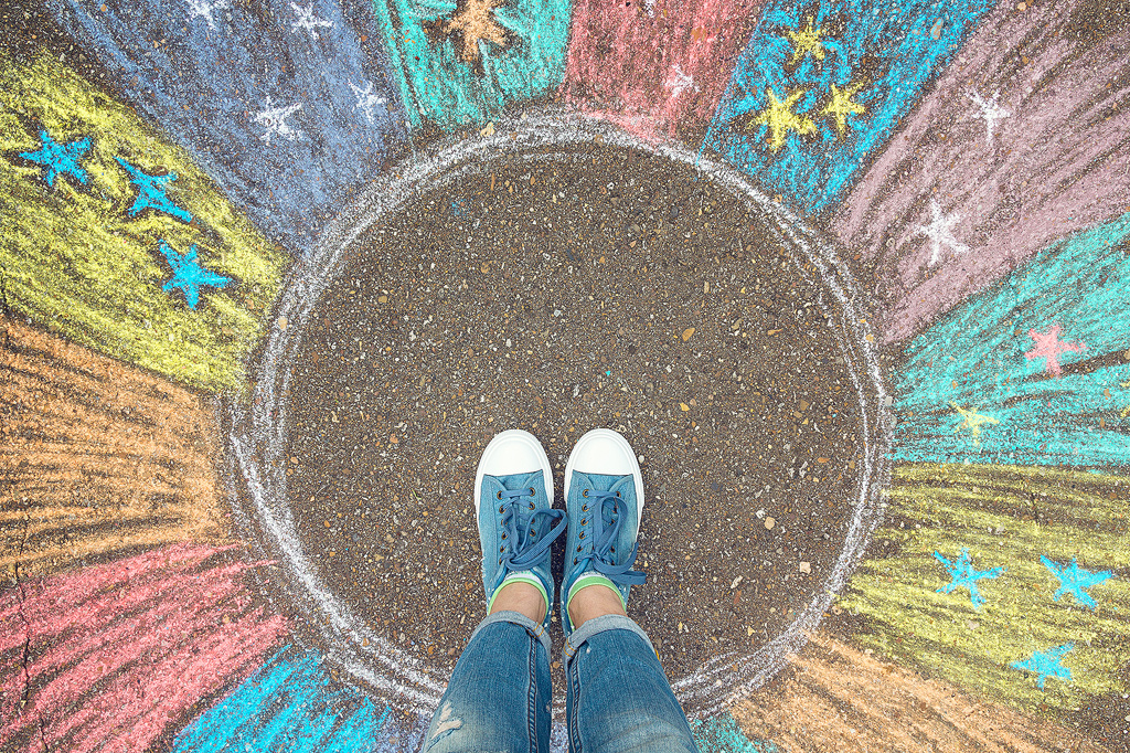 Une photo illustrative de la zone de confort. Des pieds sur une zone non tracée, entourés de couleurs éclatantes et d'étoiles, montrant le concept de sortir de sa zone de confort.