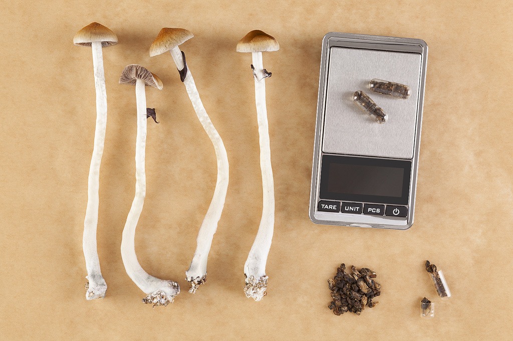 Champignons, capsules et balance, posés sur une table.